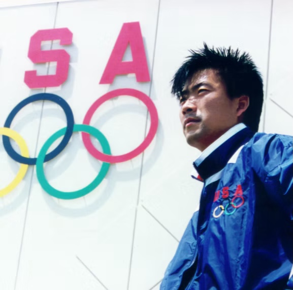 Young Bill Cho representing Team USA in front of the Olympic rings